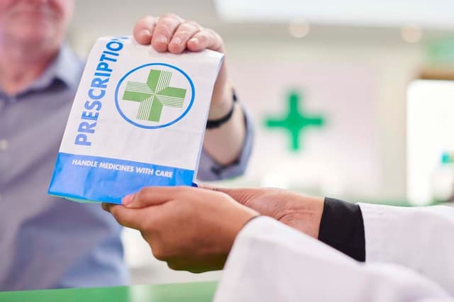 Man collecting prescription from pharmacist
